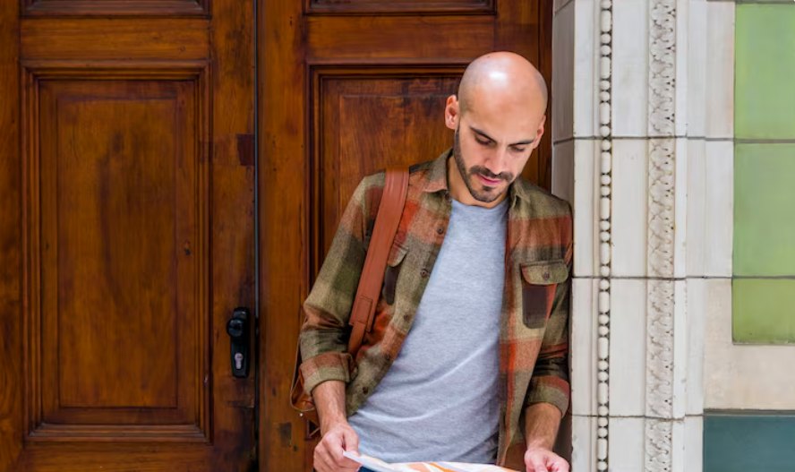 A man in a plaid shirt reading papers beside a wooden door