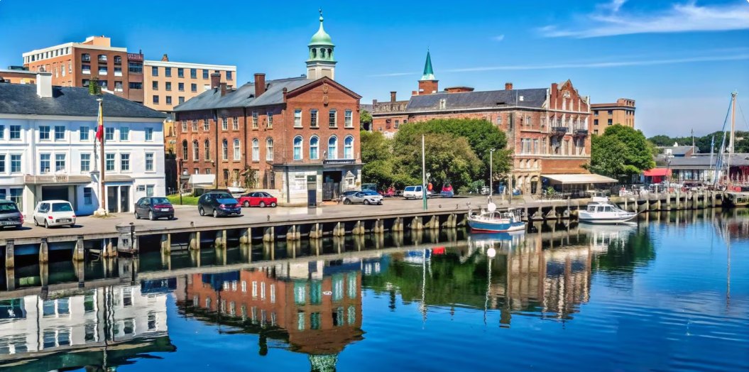 A harbor with historic brick buildings reflected in calm blue water